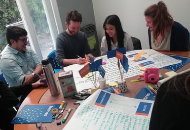 ChatGPT Plus  Personas trabajando en grupo alrededor de una mesa con afiches, marcadores y materiale