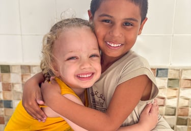 a boy and girl hugging each other on a tiled floor