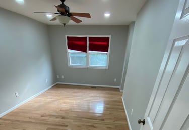 Bedroom with ceiling fan, red shades, and glossy hardwood floorboards