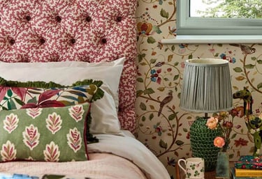 Une chambre avec un lit et une tête de lit capitonnée et deux coussins près d'une table de chevet