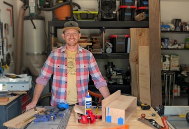 doug farrell profile picture in workship with tools, workbench and wood stacks in background