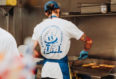 Cuiner de Flipa Burger preparant hamburgueses a la planxa amb l’uniforme de la marca