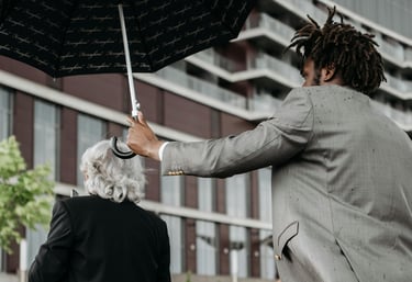 a private chauffeur protecting a woman (his client) from the rain using an umbrella