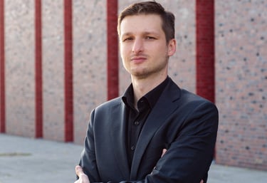 a man in a suit and tie standing in front of a brick wall