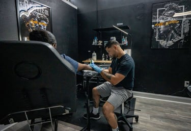tattoo artist giving a tattoo to client in private tattoo booth
