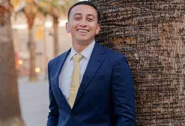a man in a suit and tie standing next to a palm tree
