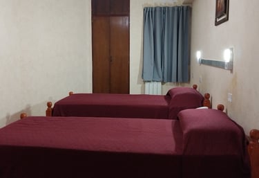 Una habitación con 2 camas y un ventilador.