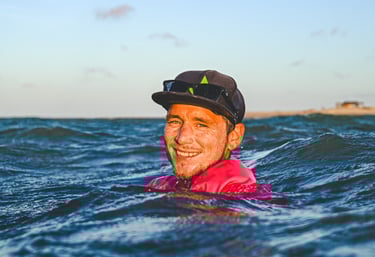 a man in a red shirt is smiling and holding a surfboard
