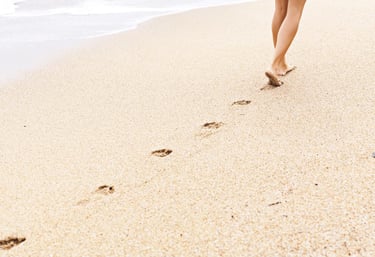 Voetafdrukken in zand op het strand bij de kustlijn.