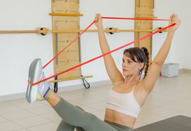 Woman doing a core exercise on a mat using a resistance band with a studio barre in the background.
