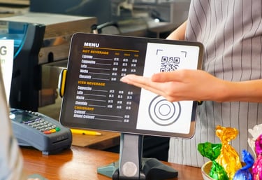 Tablet POS screen showing menu and QR code on café counter. Turn tablets into kiosk menus.