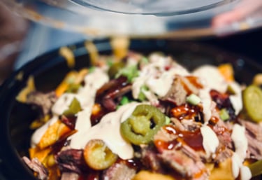 BBQ brisket nachos topped with cheddar cheese sauce, jalapeños, green onions, and house BBQ drizzle—Not Yo Mama’s Nachos, bol