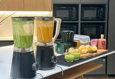 Mobilus vaisių baras ofise – šviežiai pagaminti žali ir oranžiniai smoothie