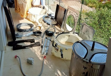 Partes de lavadoras y repuestos sobre una mesa, ilustrando el servicio técnico de reparación