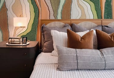 Modern bedroom featuring an earthy Aboriginal dot art wallpaper behind a wooden headboard with neutral bedding.