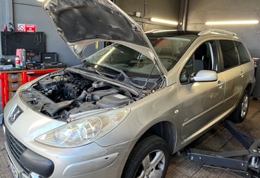 a car with a in a garage with mechanics working on it