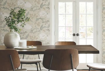 Modern dining room featuring floral wallpaper, a wood table, and mid-century chairs by French doors.