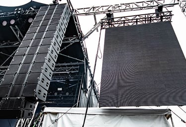 A large line array hanging from a mobile structure (Stageline) beside a LED Wall