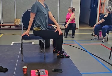Dames in een zittende twist, op een stoel, in een gymzaal