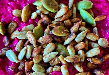A creamy bowl of huumus topped with crunchy seeds 