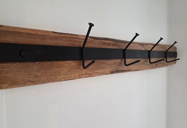 Wandgarderobe aus rustikalem Altholz mit schwarzem Metallband und vier massiven Eisenhaken im Industrial-Look.