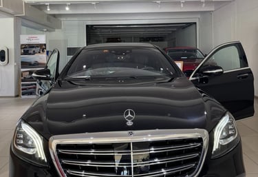 Black Mercedes S-Class with open doors in the hall of a carselling Store
