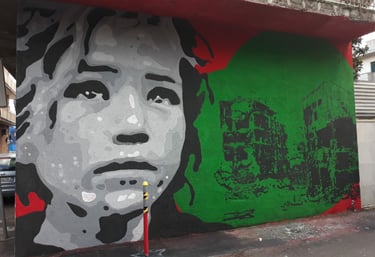 Murales a tema sociale con volto femminile e palazzi distrutti, arte urbana firmata Poliops.
