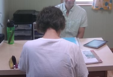 man sitting at table teaching English to older woman