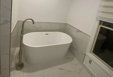 Modern bathroom with freestanding white bathtub and marble-look tiles