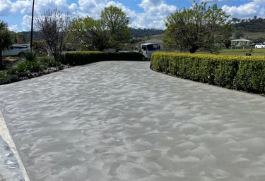 Freshly poured decorative concrete driveway with hand-troweled swirl finish in a residential landscape.