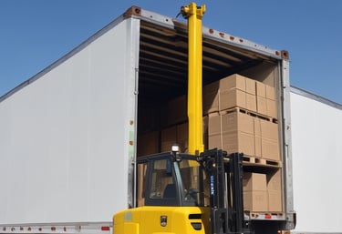 A freight train with a locomotive painted in white, orange, and blue, pulling a cargo container. The train is on a set of railway tracks with electric lines overhead and some industrial elements in the background. A few cables and parts of a motorcycle are visible in the foreground.