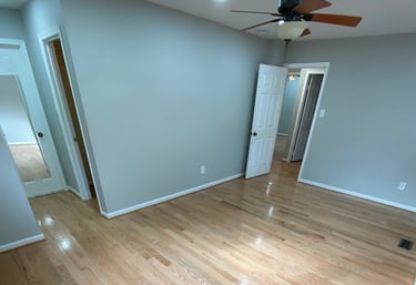 Wide bedroom view showing refinished hardwood flooring and white trim