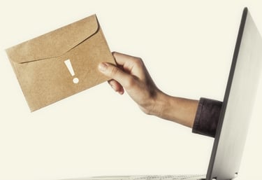 Main tendant une enveloppe kraft depuis un écran d'ordinateur — inscrivez-vous à l'infolettre Marion Communication