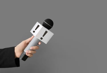 Main en veston noir tenant un microphone de journaliste — prise de parole publique et relations médias professionnelles