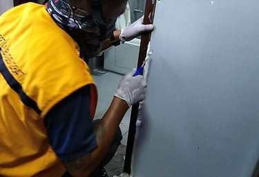 Professional technician applying white silicone sealant to a door frame during bathroom repairs.