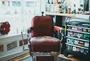 Vintage red leather barber chair in a retro barbershop with punk rock stickers and license plates.