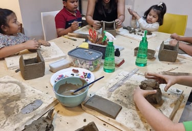 A pottery workshop where a teacher guides children in creating clay sculptures, enhancing fine motor skills and creativity.
