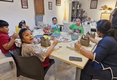 Children and a teacher engaged in a creative teracotta clay sculptures at a pottery studio table.