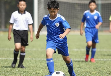 Kids from different backgrounds passing the ball together on a green soccer field.