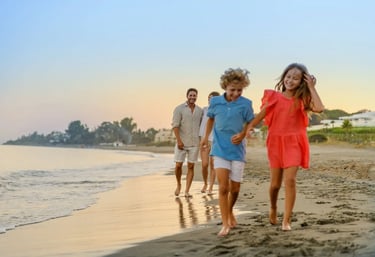 A happy family with young children walking on a sandy beach during a golden sunset vacation.