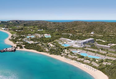 Aerial view of a luxury beachfront Ikos Aria, turquoise ocean water, and sandy beach.