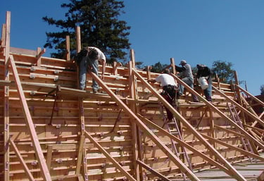 Construction crew assembling a wooden wall formwork system for a concrete foundation project.