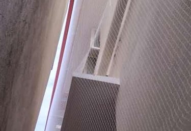 Technician carefully installing a sturdy pigeon net on a residential balcony in Hebbal.