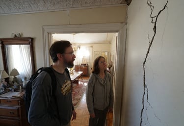Two people inspecting a large wall crack above a doorway inside an older home in Virginia