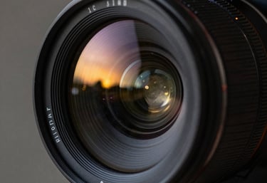 A close-up of a high-end cinema camera lens with reflections of a sunset. The mood is sophisticated and artistic. Global / International.