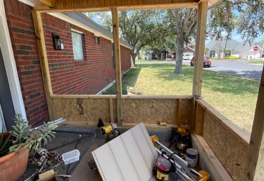 A backyard porch renovation under construction with new wood ceiling and screen enclosure framing.