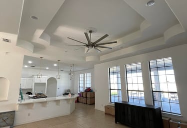 Spacious open concept living room with modern tray ceiling, large windows, and breakfast bar.