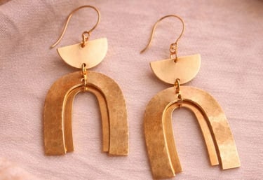 Pendientes de arco dorados hechos a mano con media luna geométrica que cuelga sobre un fon