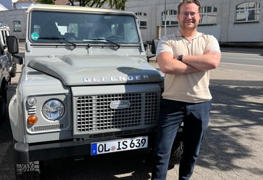  Marcel Serré, organisator van ROUTES oldtimer rally, naast een klassieke Land Rover Defender