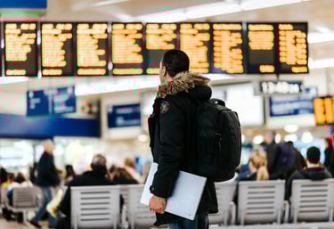 a man in a black jacket and a backpacker in a waiting area
